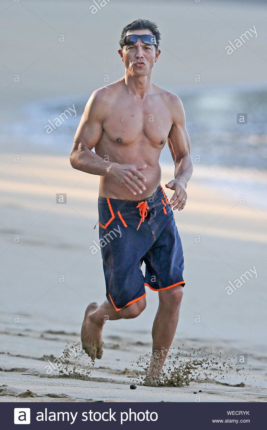 Com uma devoção
à incredulidade
,
 Sagitário mostrando seu corpo nu, com forma atlética na praia
