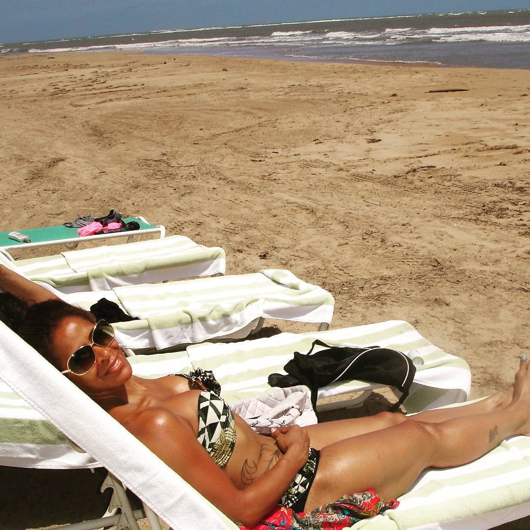 Med henne smal kropp och Mörk brun hårtyp utan behå (kupstorlek B) på stranden i bikini
